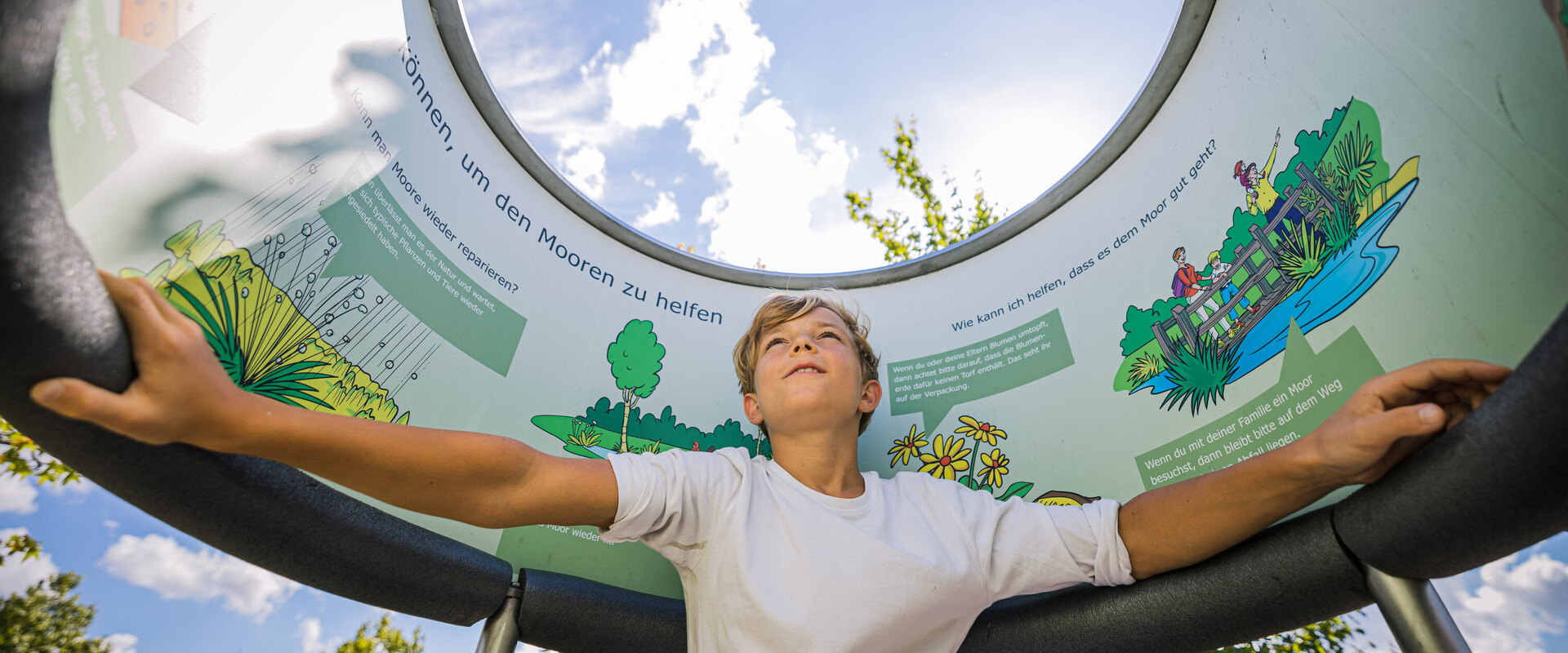 Junge in einem Element der Au&szlig;enausstellung beim Betrachten von Infotafeln.